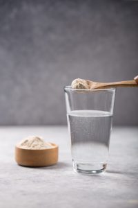 Wasserglas mit Kollagen Puder und Löffel